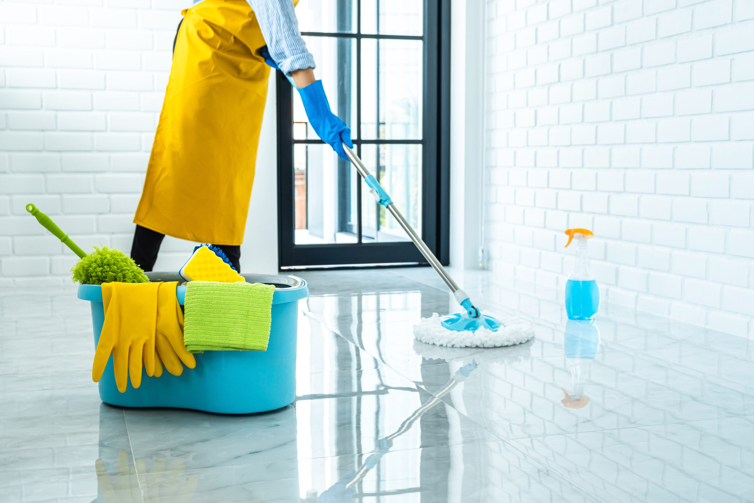 Wife housekeeping and cleaning concept, Happy young woman in blue rubber gloves wiping dust using mop while cleaning on floor at home.